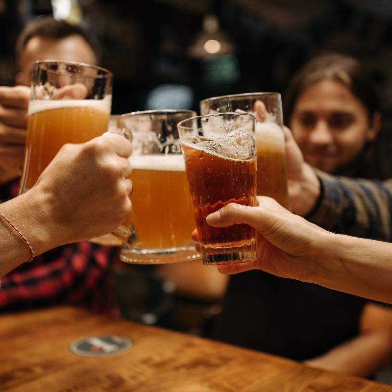 people at a bar cheers-ing beers